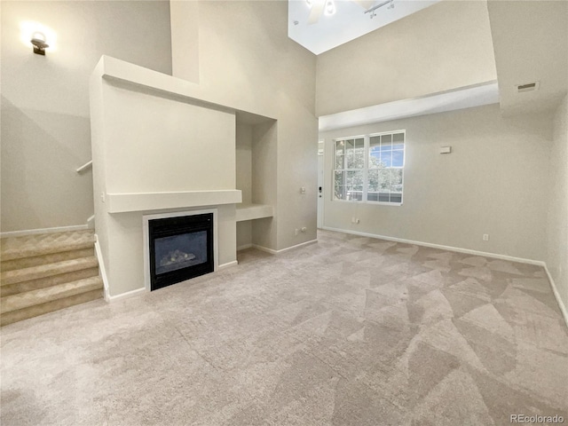 unfurnished living room featuring a high ceiling and light colored carpet