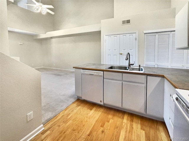 kitchen with sink, a high ceiling, white dishwasher, ceiling fan, and light carpet