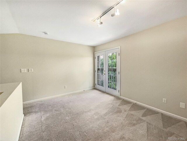 spare room with lofted ceiling, carpet flooring, baseboards, french doors, and rail lighting