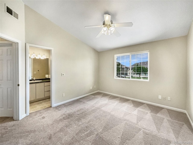 unfurnished bedroom featuring light colored carpet, visible vents, baseboards, vaulted ceiling, and ensuite bath