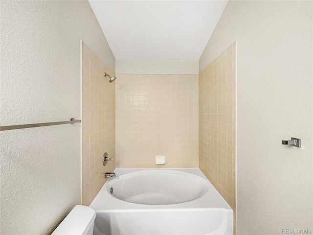 bathroom featuring toilet, tiled shower / bath combo, and vaulted ceiling