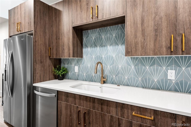 kitchen with appliances with stainless steel finishes, a sink, light countertops, tasteful backsplash, and dark brown cabinetry