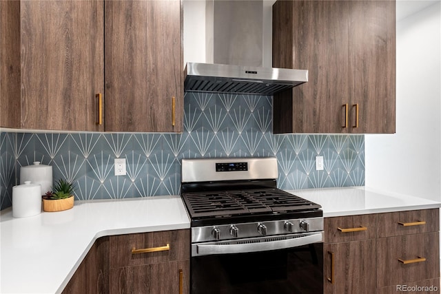 kitchen with stainless steel gas stove, wall chimney range hood, light countertops, and modern cabinets