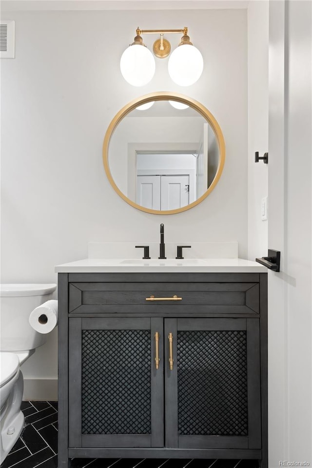 half bathroom with vanity, toilet, tile patterned floors, and baseboards