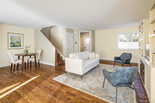 living room featuring stairway, dark wood finished floors, and baseboards