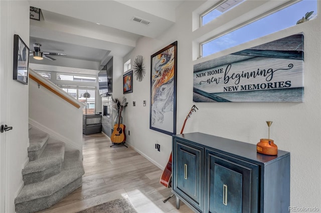 corridor featuring stairway, visible vents, plenty of natural light, and light wood-style flooring