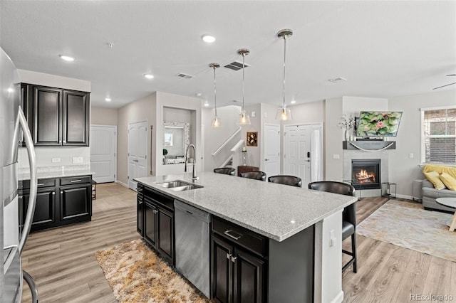 kitchen with a kitchen breakfast bar, sink, an island with sink, decorative light fixtures, and stainless steel appliances