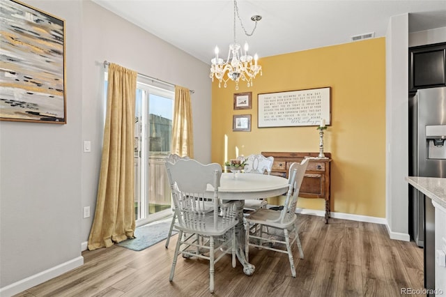 dining area with light wood-type flooring and an inviting chandelier