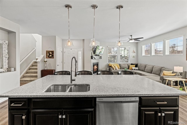 kitchen with an island with sink, stainless steel dishwasher, ceiling fan, and sink