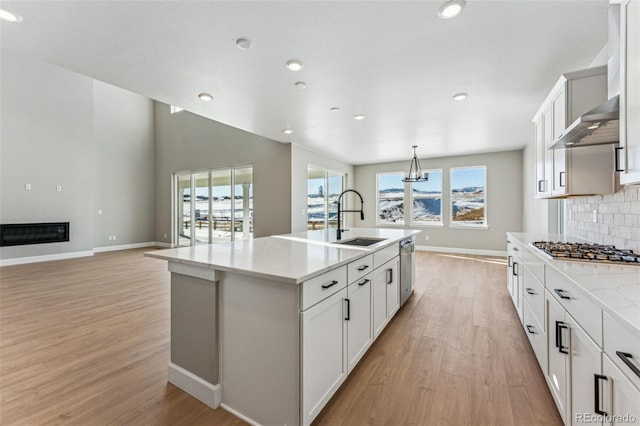 kitchen featuring stainless steel appliances, white cabinetry, a kitchen island with sink, and sink