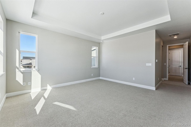 carpeted empty room with a tray ceiling