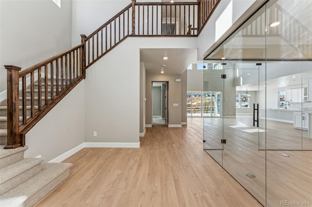 staircase featuring sink, hardwood / wood-style flooring, and a high ceiling