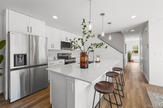1337 N Alton St, Aurora, CO 80010 - kitchen with stainless steel appliances, dark wood finished floors, white cabinets, a breakfast bar area, and a center island with sink
