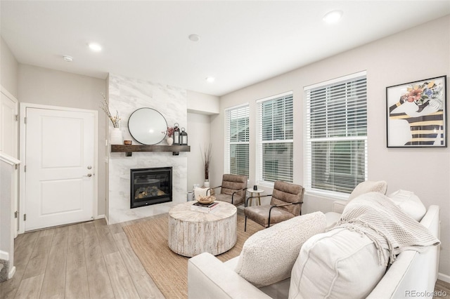 living room featuring light wood-type flooring and a high end fireplace