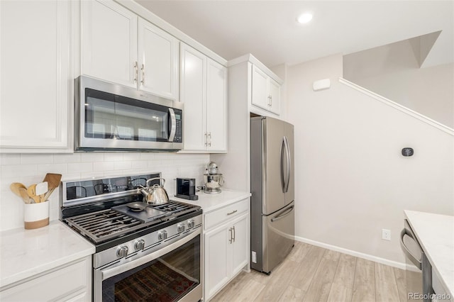 kitchen featuring white cabinets, appliances with stainless steel finishes, decorative backsplash, and light hardwood / wood-style flooring