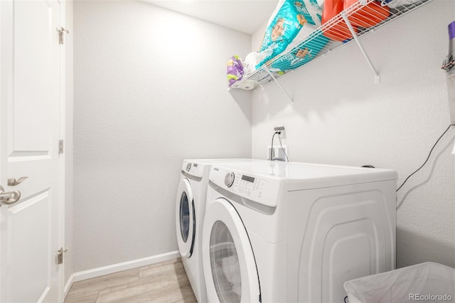 laundry room with washer and clothes dryer and light hardwood / wood-style flooring