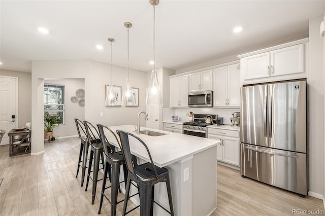 kitchen with sink, an island with sink, appliances with stainless steel finishes, decorative light fixtures, and white cabinetry