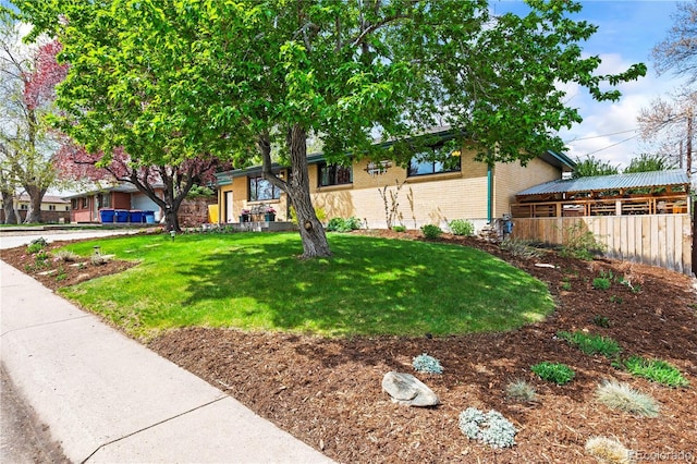 view of front of home featuring a front yard, brick siding, and fence
