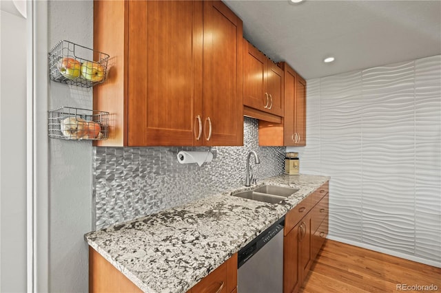 kitchen with a sink, backsplash, light stone counters, and dishwasher