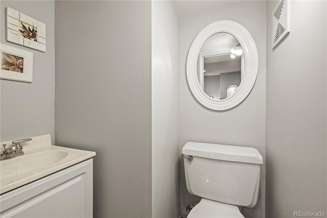 half bath with toilet, vanity, and visible vents