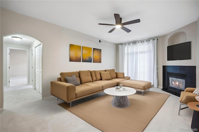 living room with light carpet, a tile fireplace, and ceiling fan