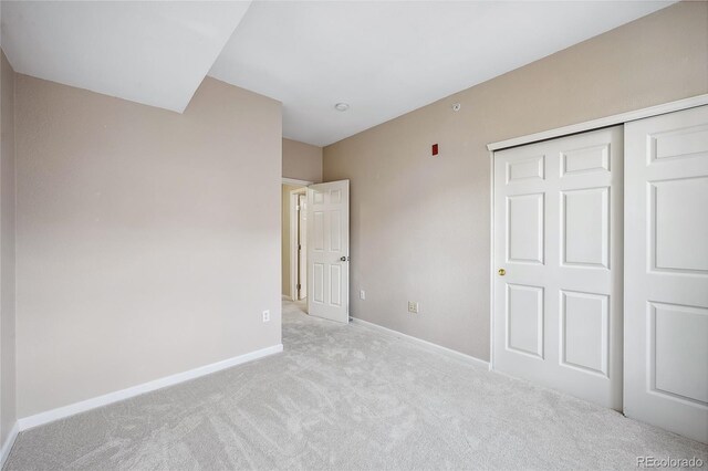 unfurnished bedroom featuring a closet and light carpet