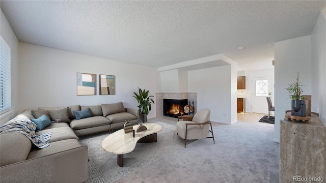 living area featuring a warm lit fireplace, a textured ceiling, and light colored carpet