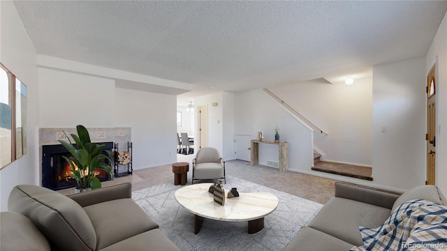 living area with a textured ceiling, a fireplace, baseboards, stairs, and carpet