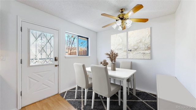 dining room featuring a textured ceiling, light wood-style flooring, and a ceiling fan