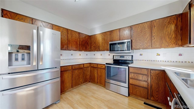 kitchen with appliances with stainless steel finishes, light countertops, brown cabinets, and decorative backsplash