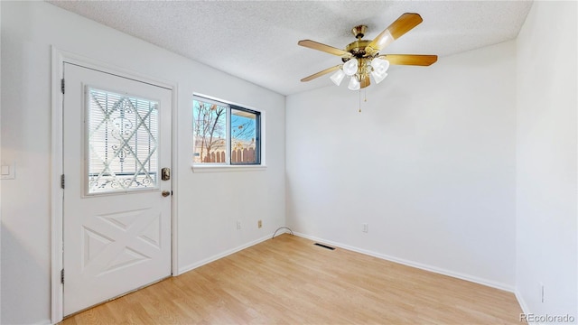 entrance foyer with light wood finished floors, baseboards, visible vents, a ceiling fan, and a textured ceiling