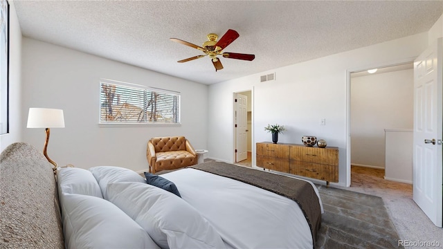 bedroom featuring carpet floors, visible vents, ceiling fan, and a textured ceiling