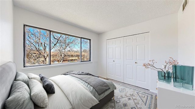 bedroom featuring a closet, visible vents, a textured ceiling, and baseboards