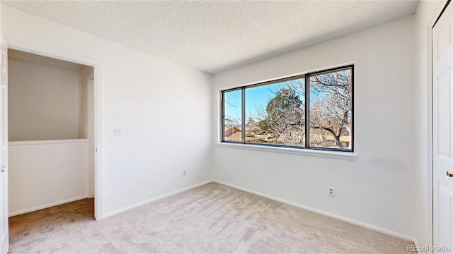 unfurnished bedroom featuring a closet, a textured ceiling, baseboards, and carpet flooring