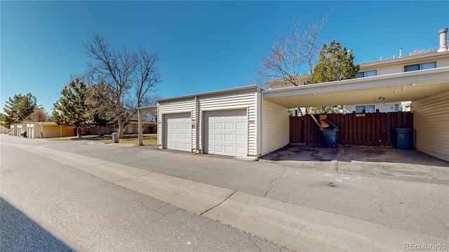 garage with a carport and fence