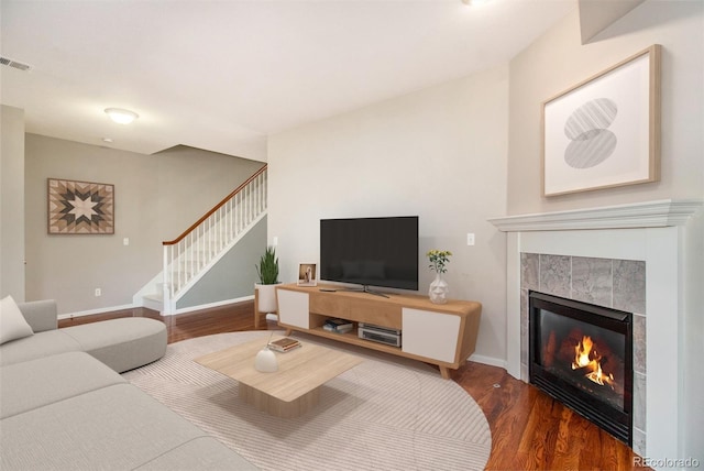 living room with a tiled fireplace and hardwood / wood-style floors