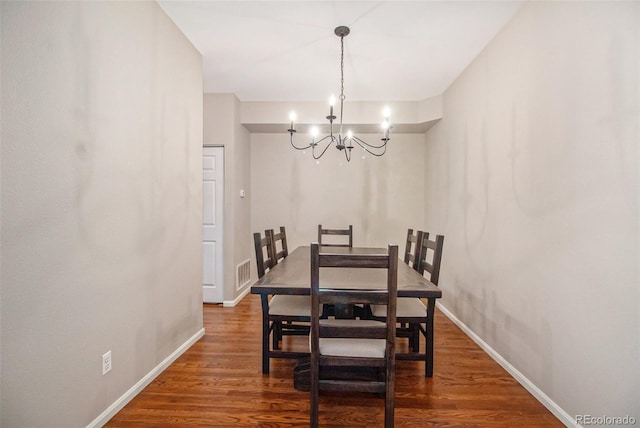 dining room with an inviting chandelier and dark wood-type flooring