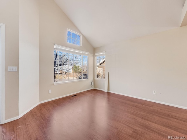 empty room featuring high vaulted ceiling, baseboards, and wood finished floors