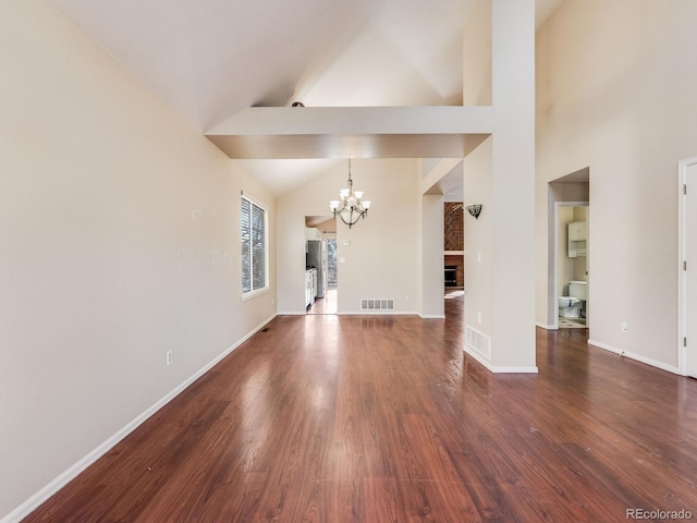 interior space with baseboards, visible vents, wood finished floors, a fireplace, and a notable chandelier