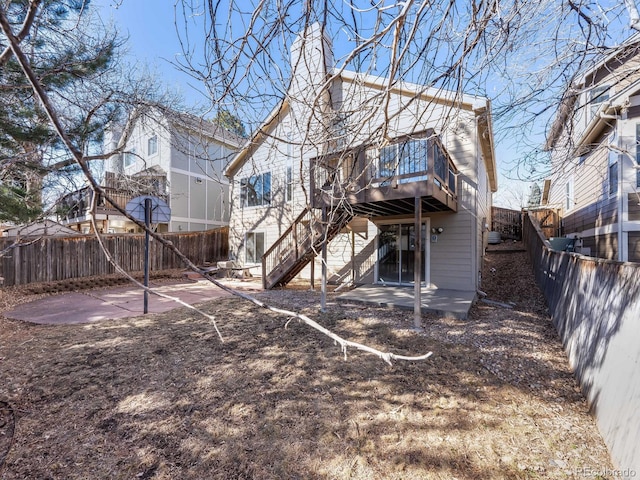 rear view of house with a fenced backyard, stairway, a wooden deck, and a patio