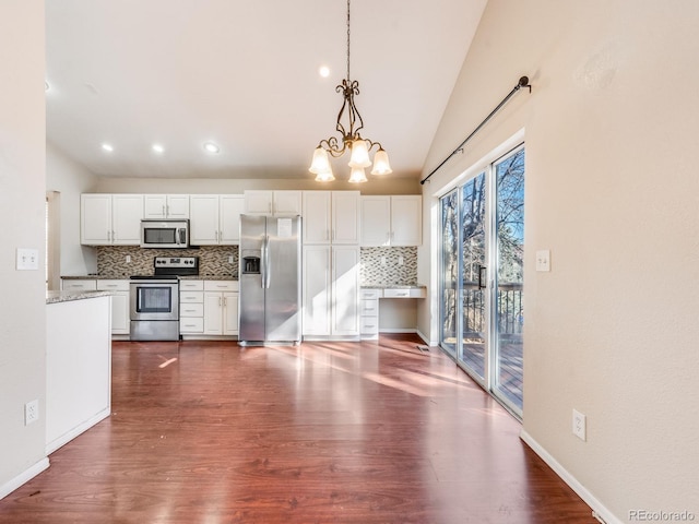 kitchen with lofted ceiling, stainless steel appliances, white cabinets, backsplash, and dark wood-style floors