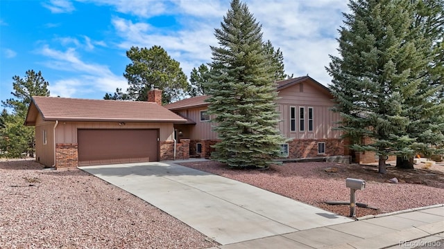 view of front facade with driveway, a chimney, a garage, a tiled roof, and brick siding