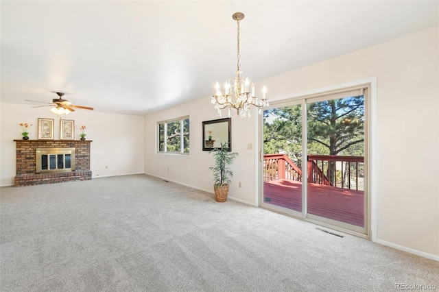 unfurnished living room featuring ceiling fan with notable chandelier, carpet, visible vents, and baseboards