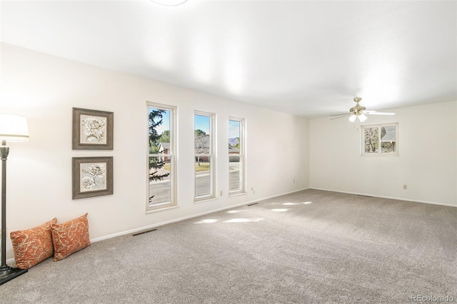 carpeted empty room featuring visible vents, baseboards, and ceiling fan