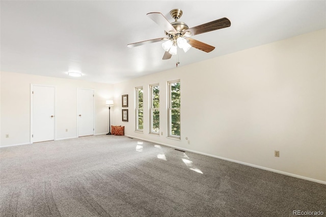 carpeted empty room featuring visible vents, a ceiling fan, and baseboards