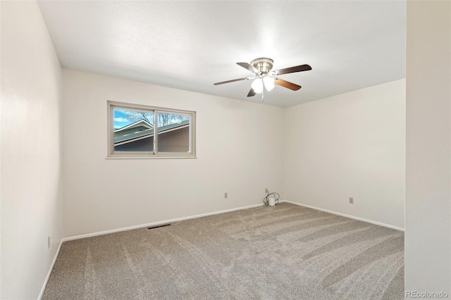 carpeted empty room with visible vents, baseboards, and a ceiling fan