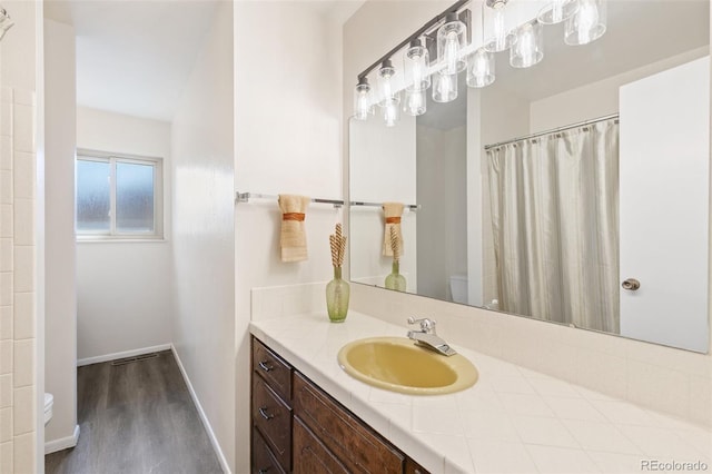 bathroom with toilet, wood finished floors, a shower with shower curtain, baseboards, and vanity