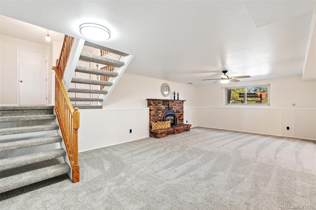 unfurnished living room featuring stairway, a wood stove, ceiling fan, and carpet flooring