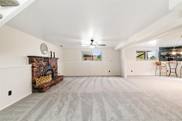 unfurnished living room featuring a wood stove, carpet floors, and ceiling fan