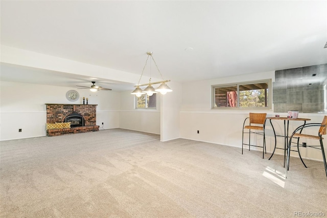 living area with a brick fireplace, a ceiling fan, and carpet floors